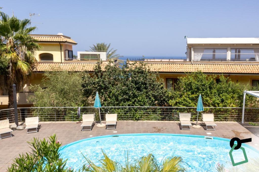a swimming pool with chairs and a building at Hotiday Tropea Parghelia in Tropea