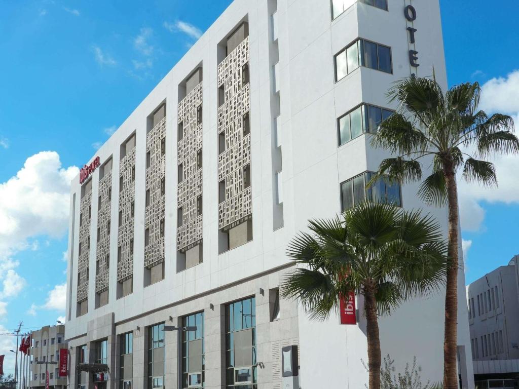 a white building with a palm tree in front of it at Ibis Sfax in Sfax