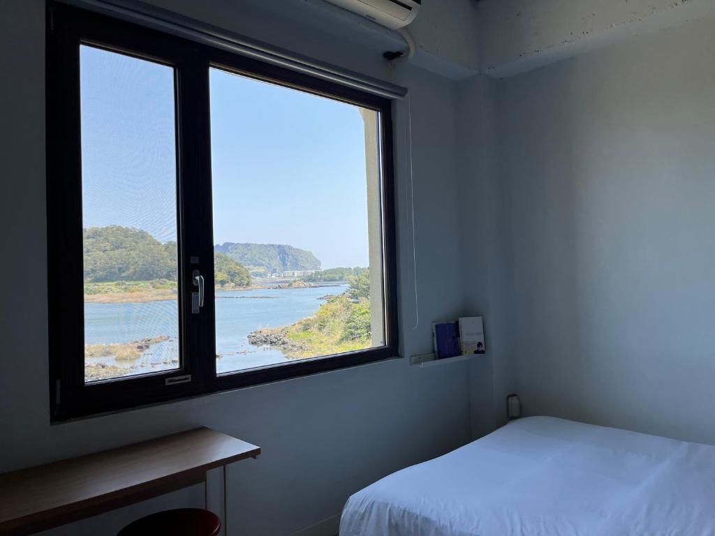 a bedroom with a window with a view of the ocean at maisonde ojolac in Kosŏng-ni