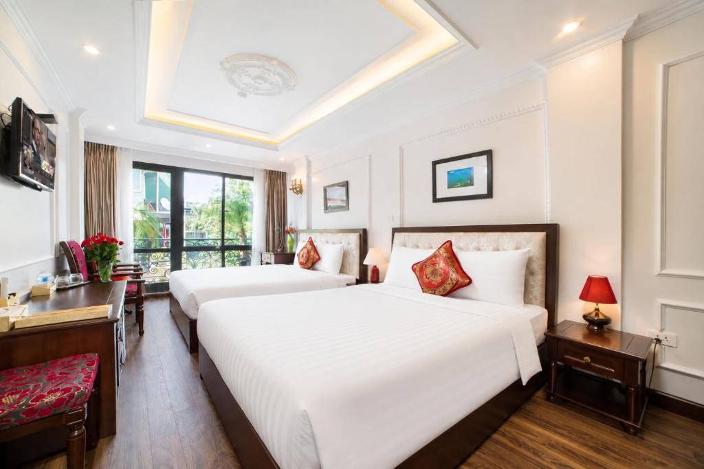 a bedroom with two beds and a desk at Golden Sail Hotel & Travel in Hanoi