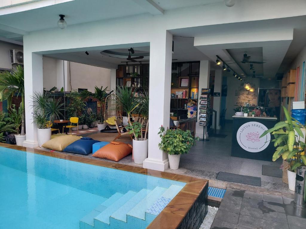 a swimming pool next to a house with plants at LOTUS SERENITY Hostel in Siem Reap