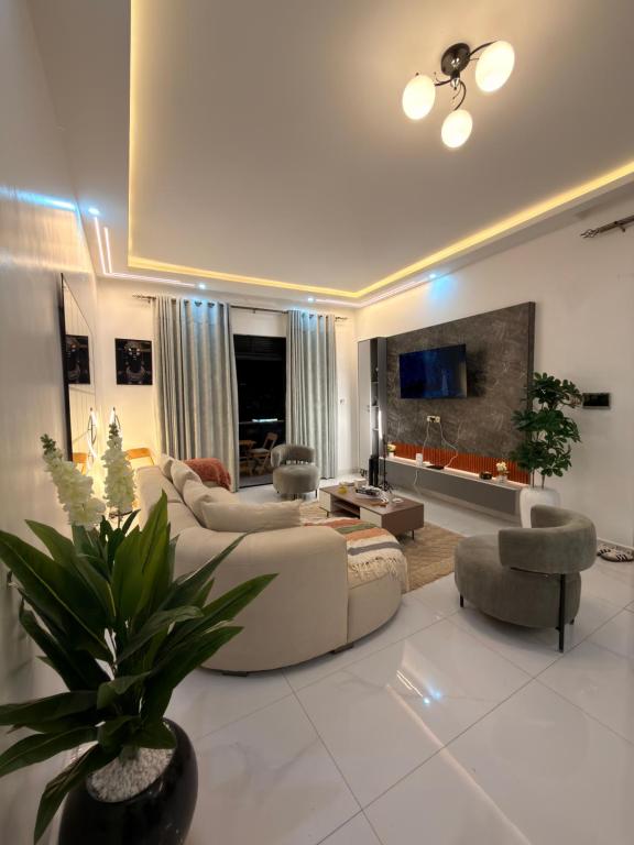 a living room with a couch and chairs and a tv at Abban homes in Kampala