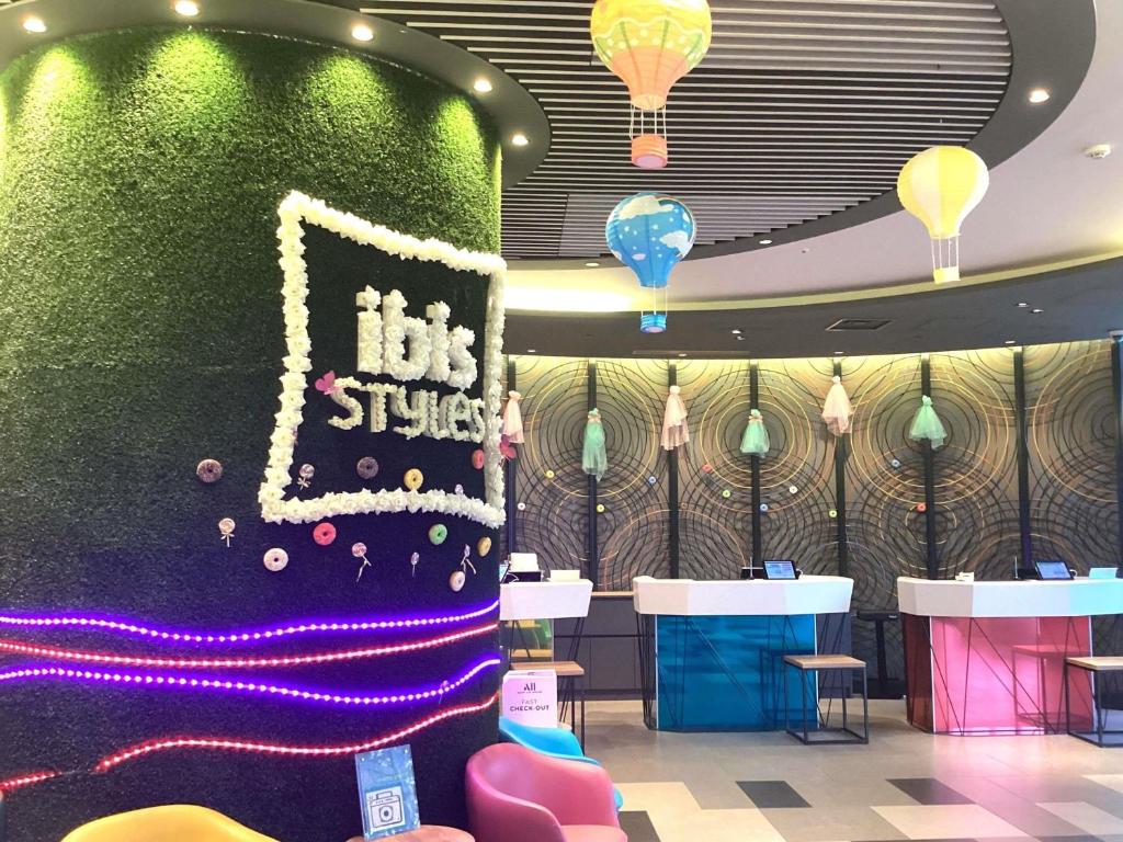 a room with a green wall and tables and chairs at ibis Styles Tokyo Bay in Urayasu