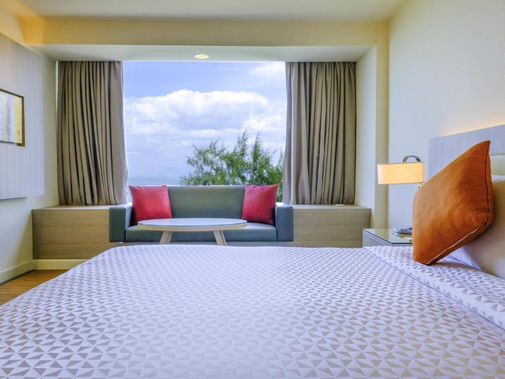 a hotel room with a large bed and a couch at Mercure Penang Beach in George Town