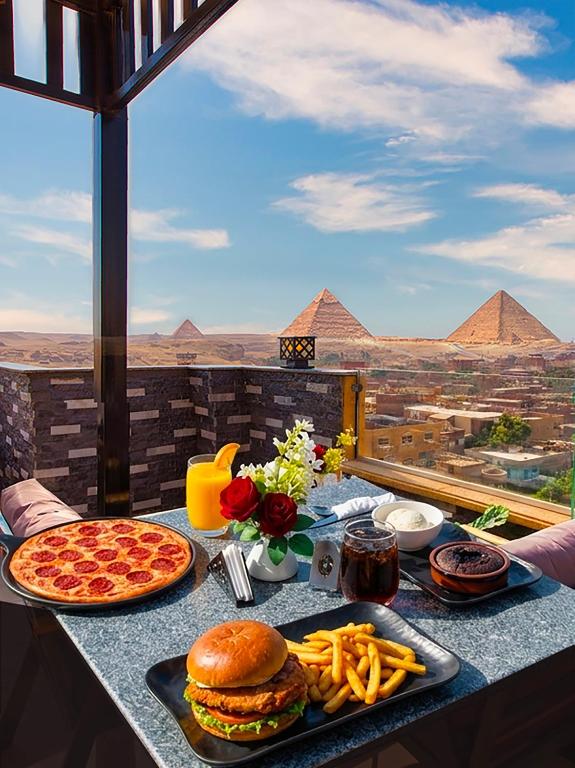a table with food on it with pyramids in the background at Premium Pyramids BoutiQue With Rooftop Access in Cairo
