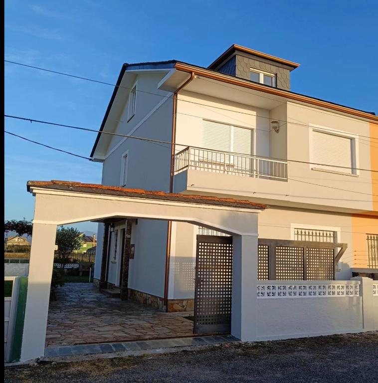 a white house with a gate in front of it at A Pedriña Ribadeo in Ribadeo