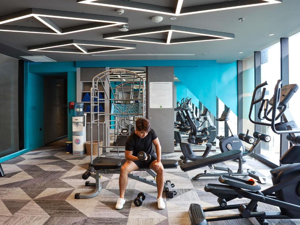 A guest using a bench in a bright gym beside cardio equipment.