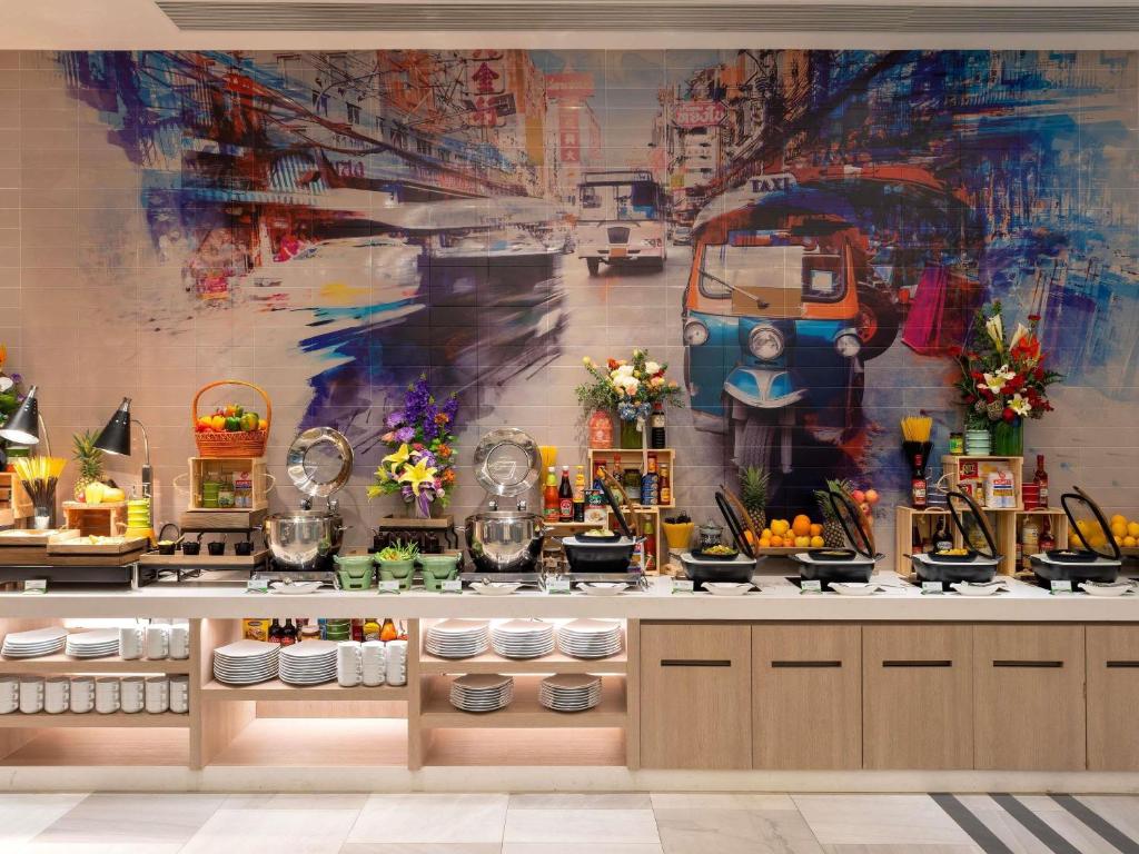 A full-width buffet counter with food stations, crockery shelves and a colorful Bangkok mural.