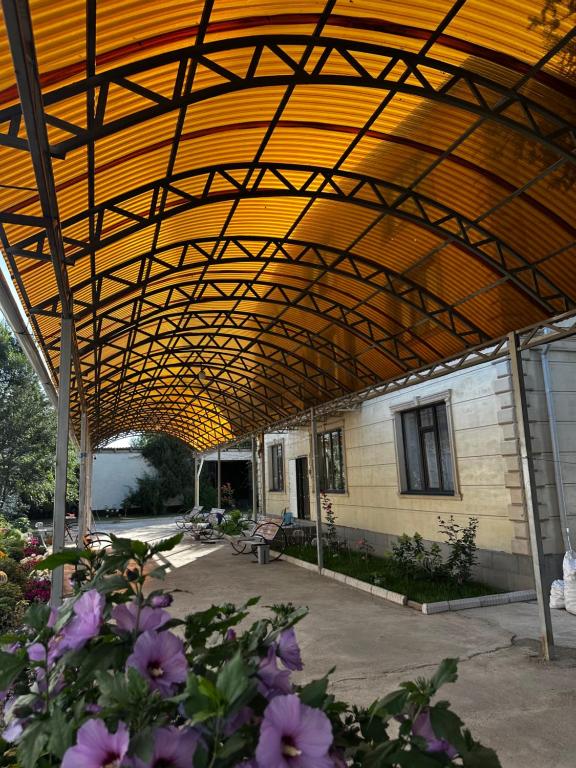 a large wooden roof over a patio with purple flowers at Guest house 97 in Karakol