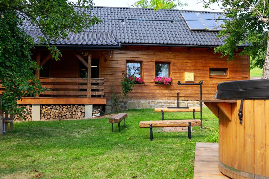 a log cabin with a picnic table and benches in the yard at Pod Dzwonkiem in Jasienica