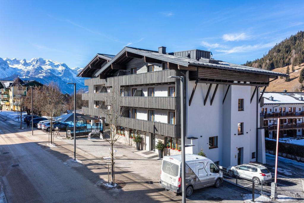 a building with a van parked in a parking lot at Apart Hotel Alpenhof Werfenweng in Werfenweng