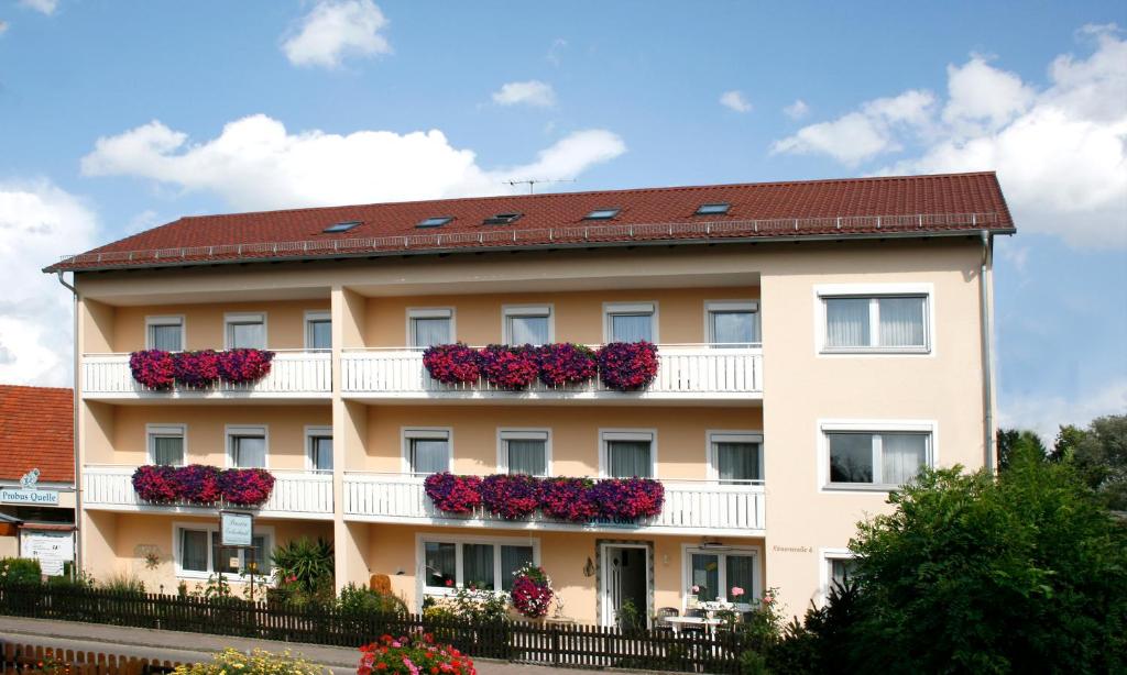 un bâtiment avec des fleurs sur les balcons dans l'établissement Pension Eichschmid / Röll´n Biergarten, à Bad Gögging