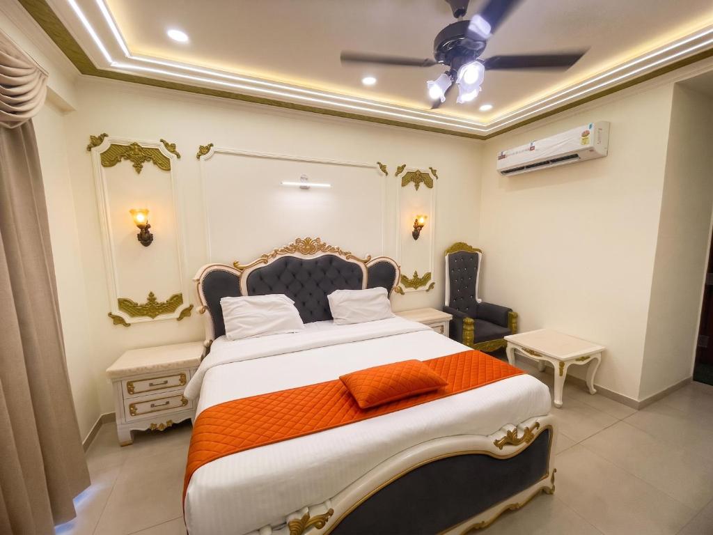 a bedroom with a large bed with an orange blanket at Hotel Om Sai Villa Gomti Nagar, Lucknow in Lucknow