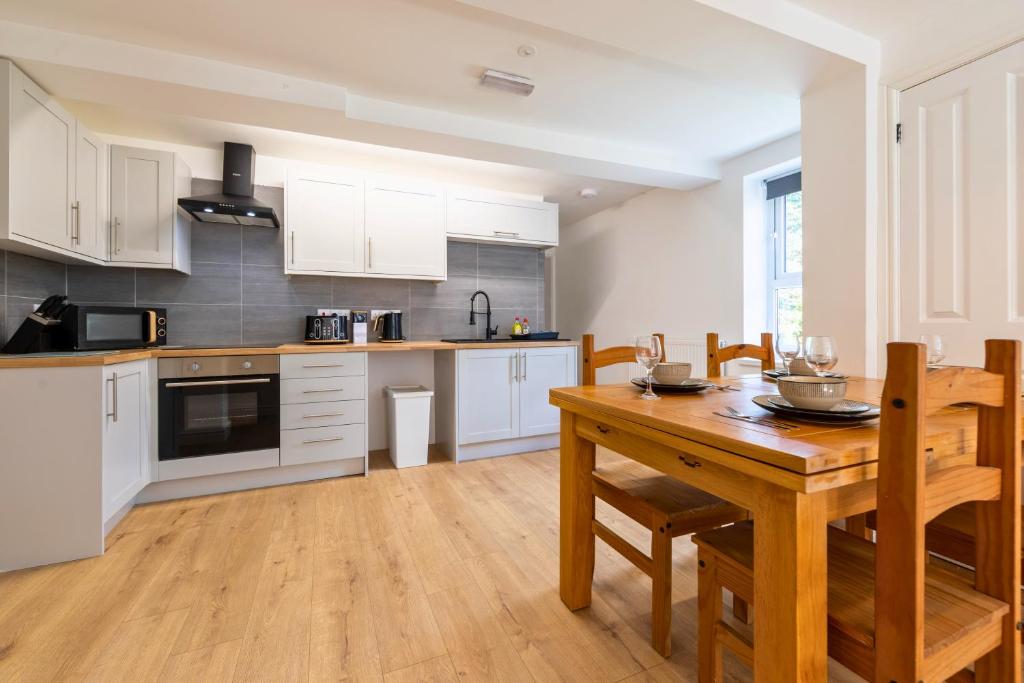 a kitchen with white cabinets and a wooden table at New 3 Bedroom Apartment Next to Station in Chepstow