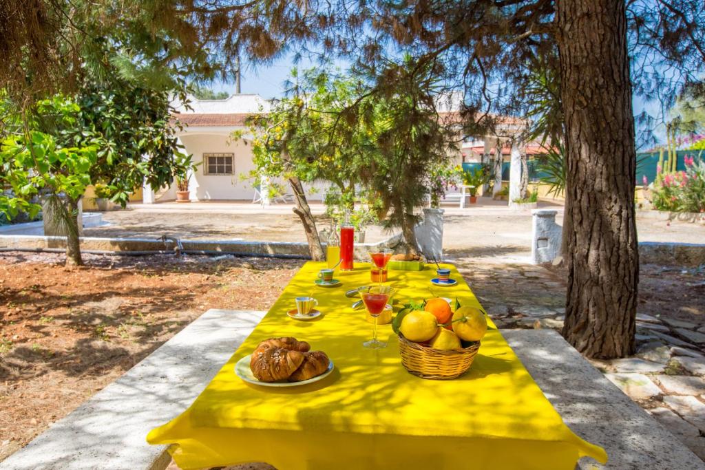 un tavolo giallo con cibo e bevande e un cesto di frutta di Casa Mediterranea dei Normanni a San Vito dei Normanni