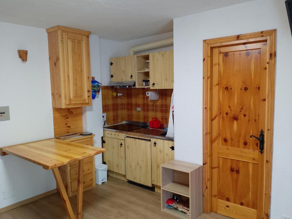 a kitchen with wooden cabinets and a wooden table at monolocale Sabrina in Torgnon