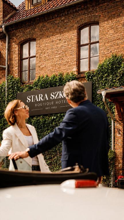 a man and woman shaking hands in front of a building at Stara Szkoła Boutique Hotel in Wronki