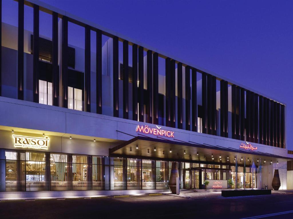 a large building with a store front at night at Mövenpick Hotel Tahlia Jeddah in Jeddah