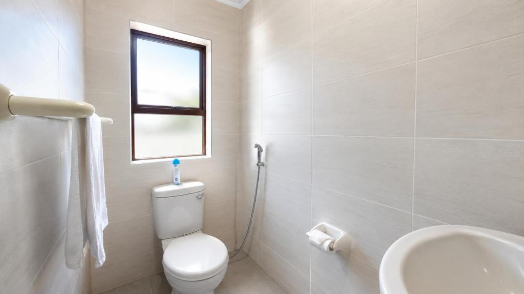 a white bathroom with a toilet and a window at Giney's View 8 Unit in Vilanculos