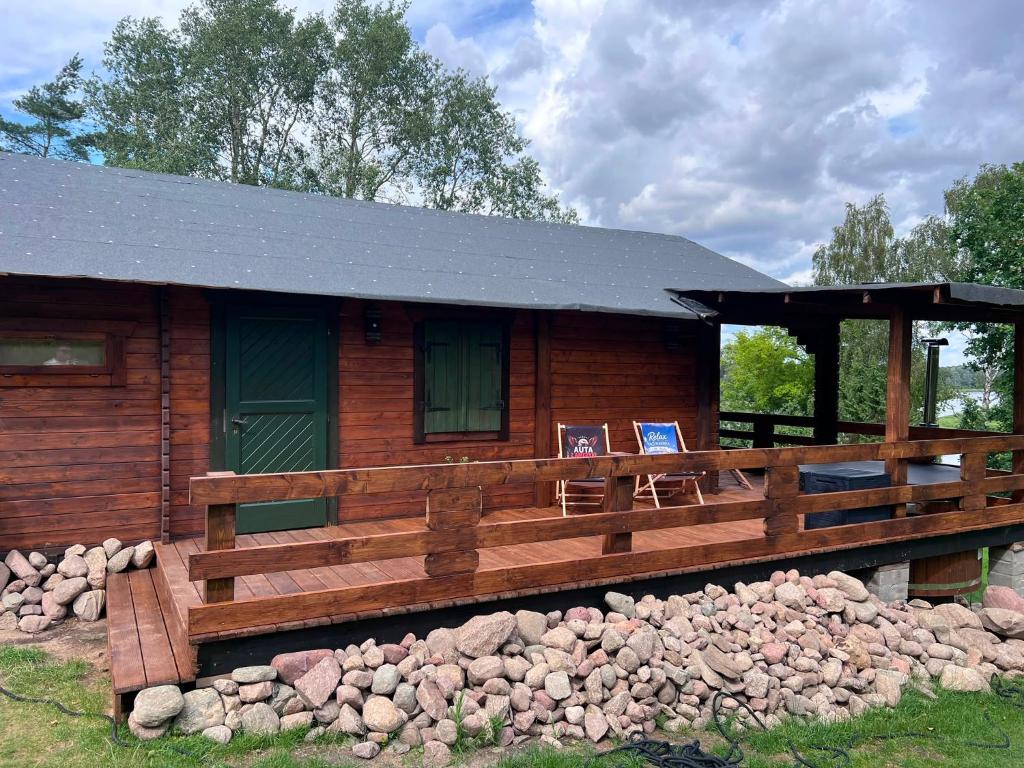 a log cabin with a porch and a fence at Relax nad Narwią u Oli Pawła in Chmielewo