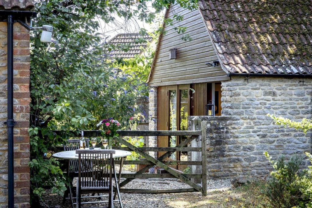 a patio with a table and chairs and a building at Finest Retreats - The Little Barn in Great Somerford