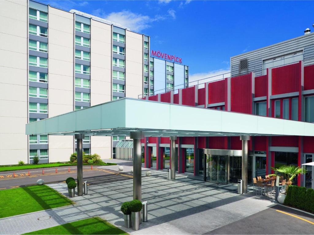 a hotel building with a glass canopy in front of it at Mövenpick Hotel Zurich Airport in Glattbrugg