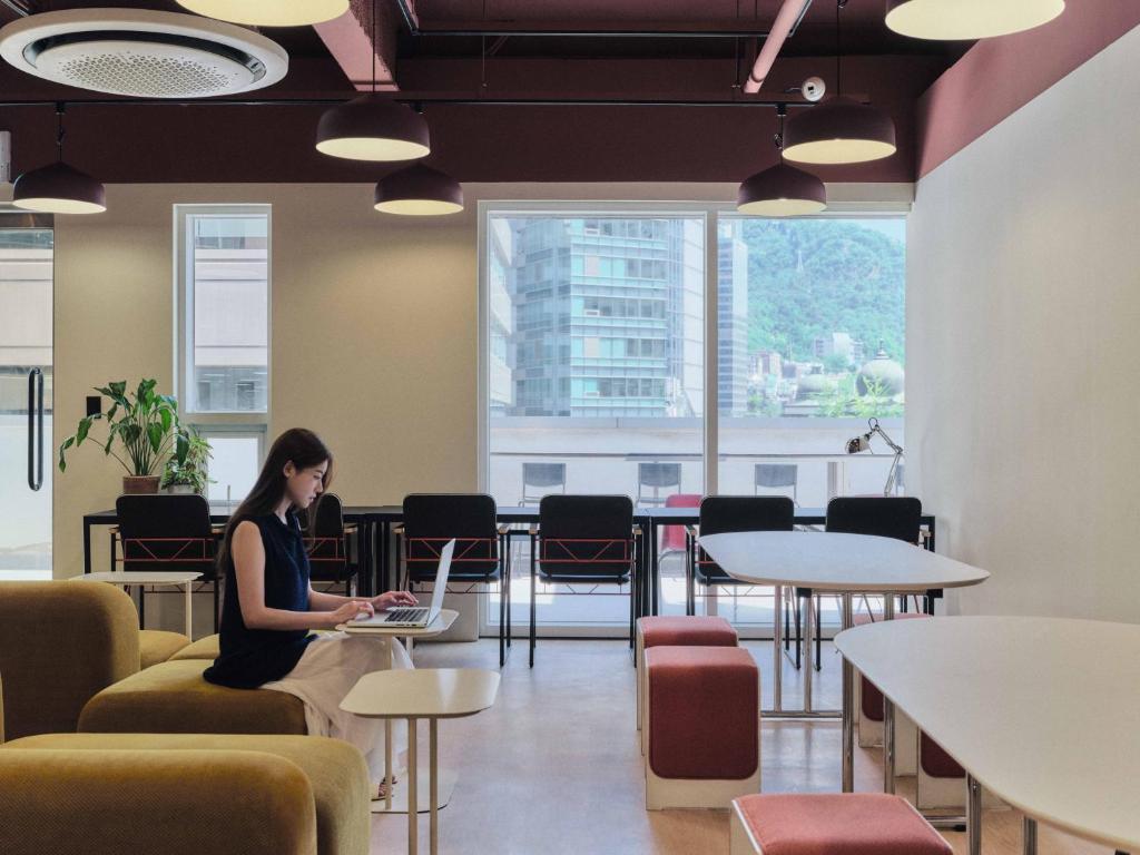 a woman sitting on a chair in a room with a laptop at Seoul ABC Hostel in Seoul