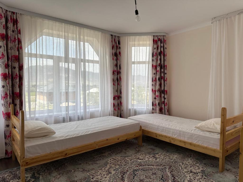 two beds in a room with a window at Kochkor valley in Kochkorka