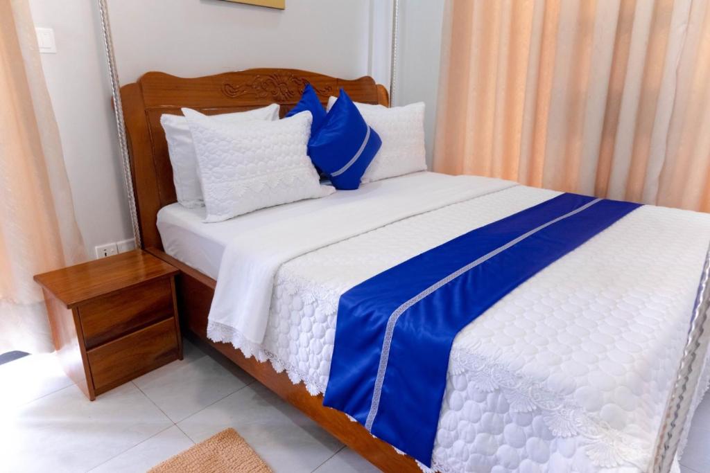a bed with blue and white sheets and pillows at Zeus Boutique Apartment in Kigali