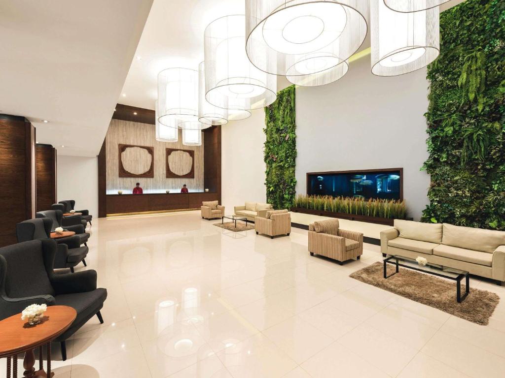 a lobby with couches chairs and a fireplace at Movenpick Suriwongse Hotel Chiang Mai in Chiang Mai