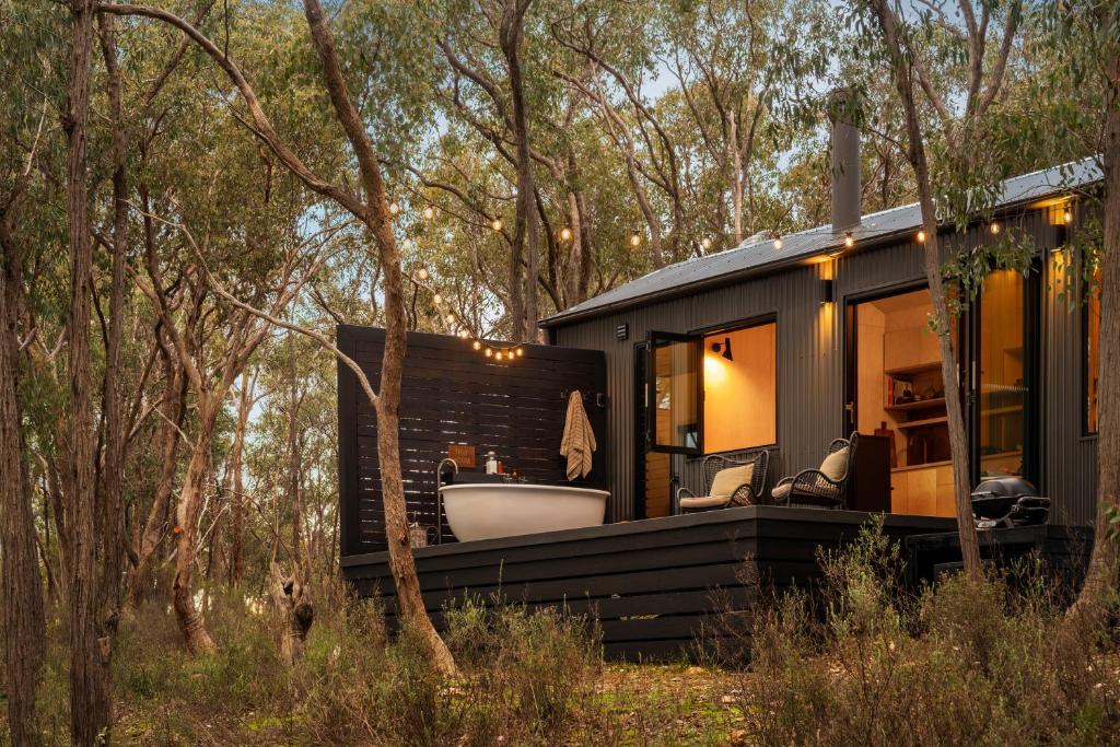 a black tiny house with a tub in the woods at HeartStone Hill - Tiny House in Castlemaine