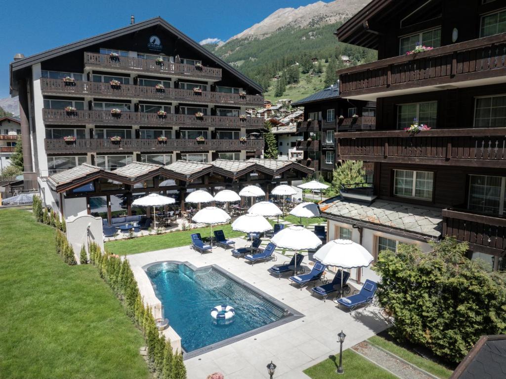 an aerial view of a hotel with a pool and umbrellas at Mirabeau Alpine in Zermatt