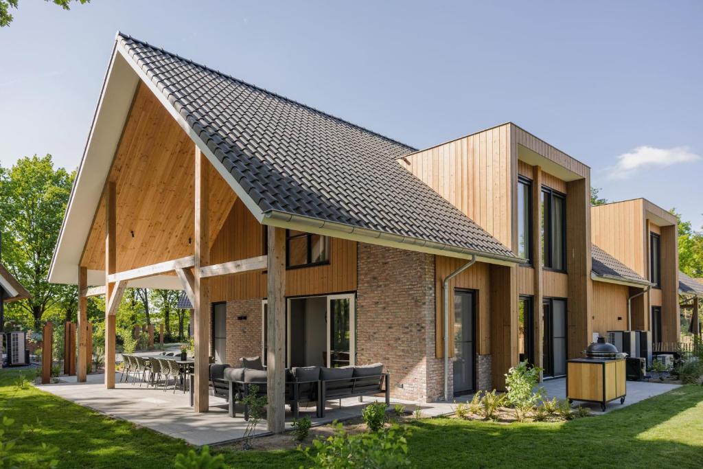 a house with a pitched roof with a patio at Veluwe Villa with Indoor Pool & Wellness | 12 persons in Wekerom