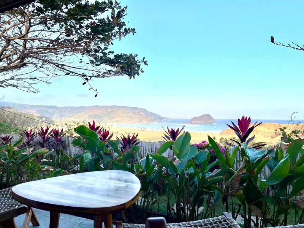 a table and chairs with a view of the ocean at The Villa Indah Areguling in Kuta Lombok