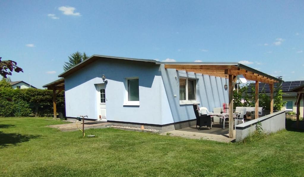 a small blue and white house in a yard at Gästehaus mit 3 separaten Schlafbereichen, Terrasse und Carport in Velten