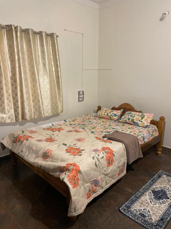 a bedroom with a bed with a floral comforter and a window at Mandira Homes in Mysore
