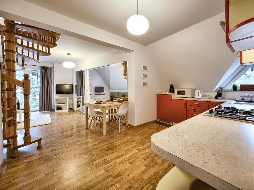 kuchnia i salon ze stołem i krzesłami w obiekcie VisitZakopane - Hill Apartment w Zakopanem