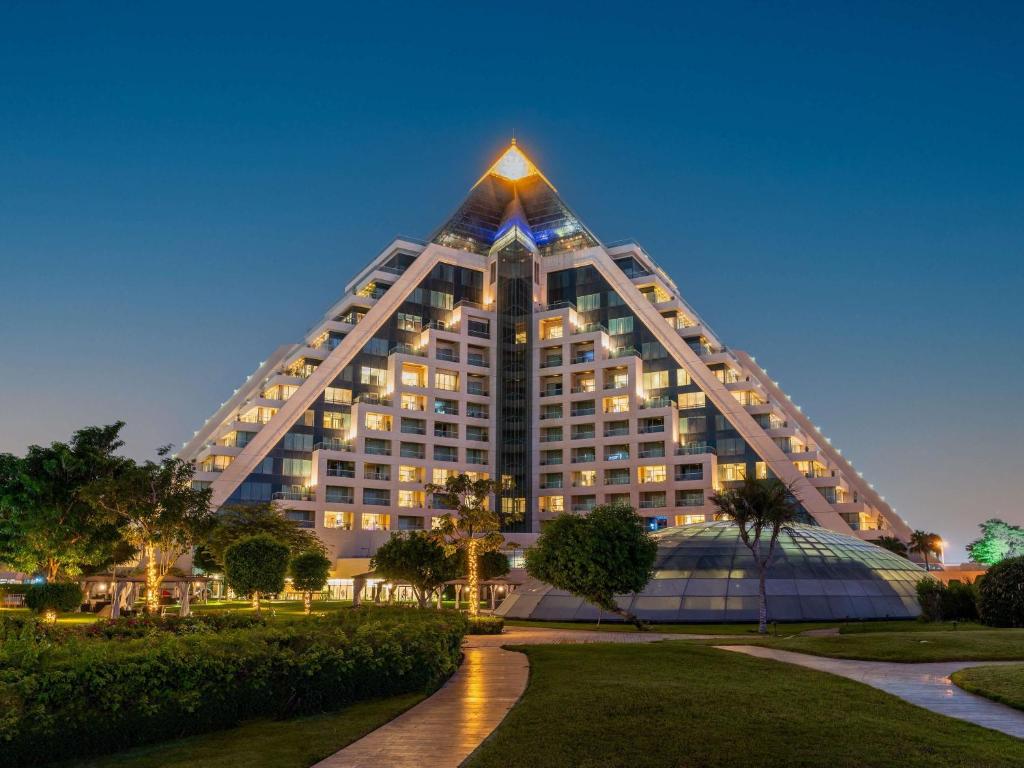 a large building with a pyramid shaped roof at night at Raffles Dubai in Dubai