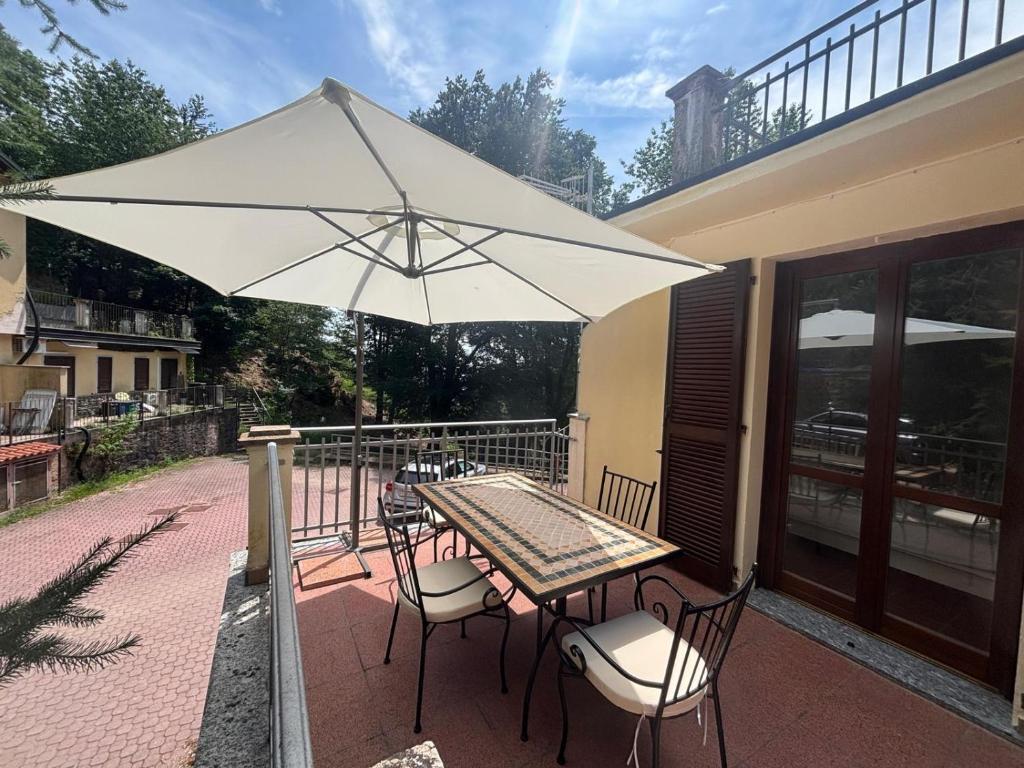 a table and chairs under an umbrella on a patio at Condominio Villa Helios in Cuasso Al Monte