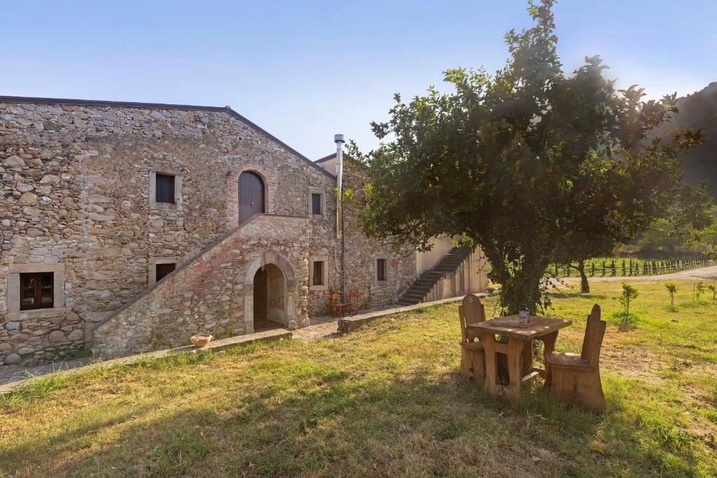 a building with a tree and a bench in front of it at Fattoria San Pio in Naso