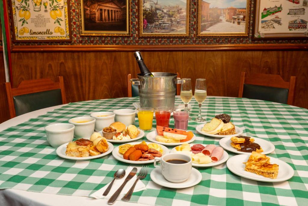 a table with plates of breakfast foods and drinks at Hotel Bella Italia in Foz do Iguaçu