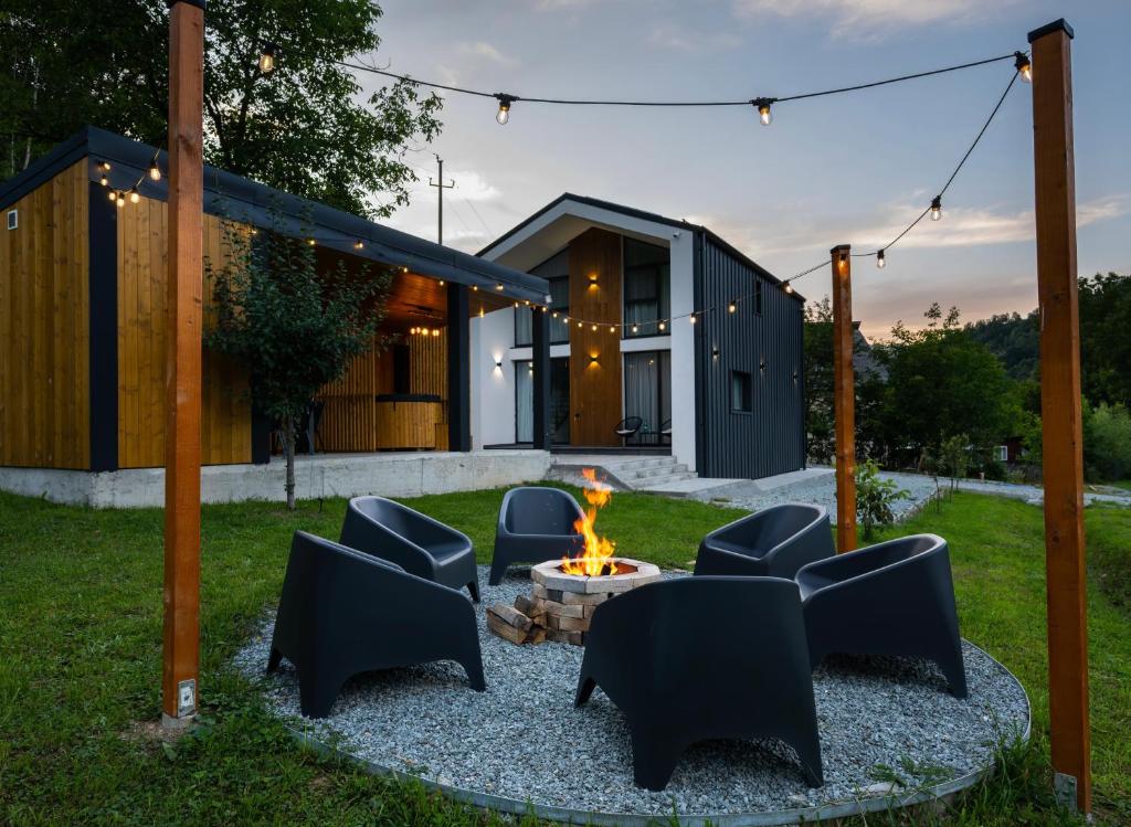 a backyard with a fire pit and chairs and a house at Cozy HillSide in Borşa