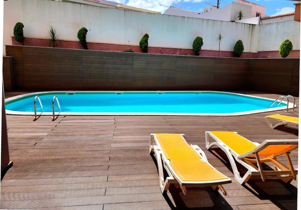 a swimming pool with two lounge chairs next to a building at Shell Bay Retreat in São Martinho do Porto