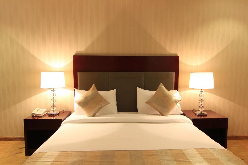 - une chambre avec un grand lit et deux lampes dans l'établissement Aliah Towlan Palace, à Riyad