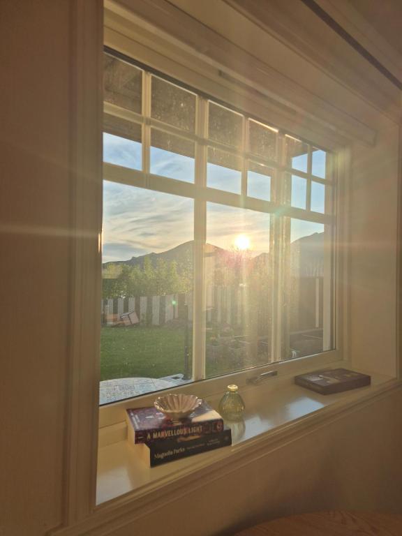 a window with a view of the sunset through it at Apartment on Leknes with a view in Vestvågøya