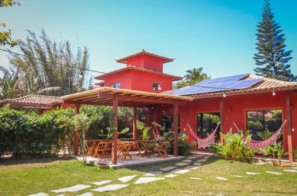 a red house with a picnic table in the yard at Hospedaria Oitis in Búzios