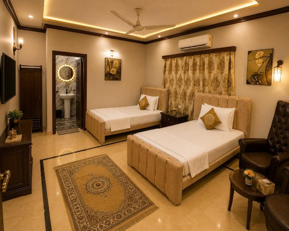 a bedroom with two beds and a chair and a couch at Beach Heaven Guest House in Karachi