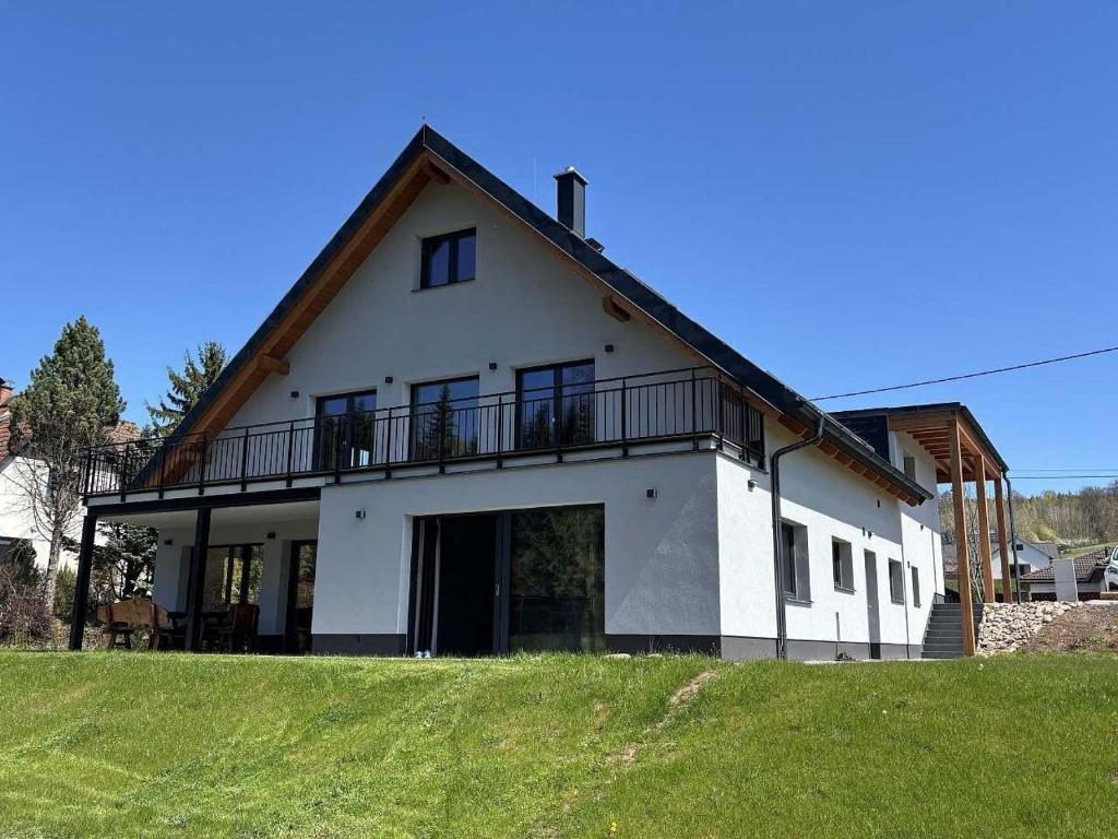a white house with a balcony on top of a field at Alpine Chalet Krkonose in Prosečné