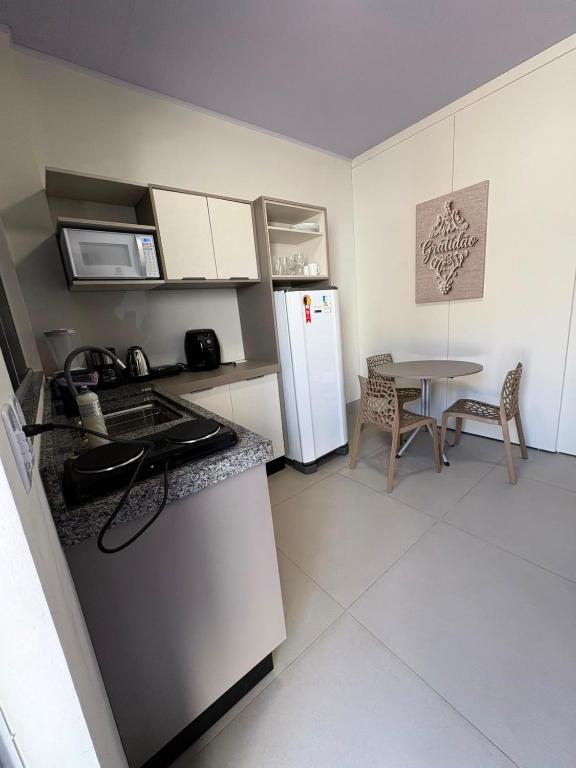 a small kitchen with a refrigerator and a table at Estúdio J&C 05 A in Primavera do Leste