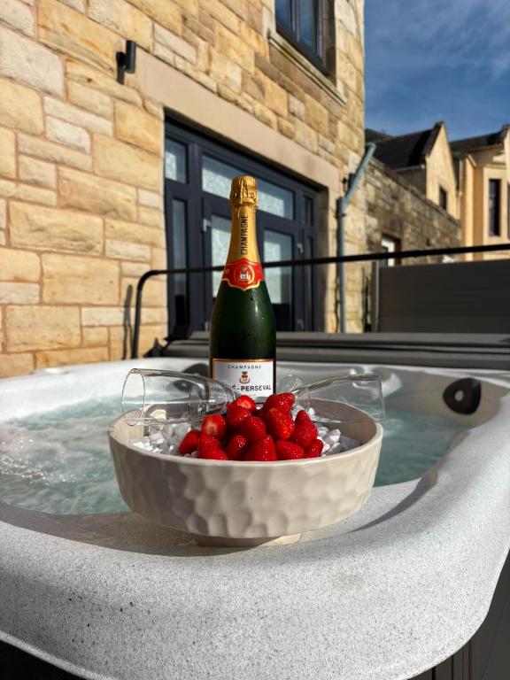 a bottle of champagne and a bowl of berries in a bath tub at Sea view Villa Holiday and Corporate Let Accommodation in Prestwick